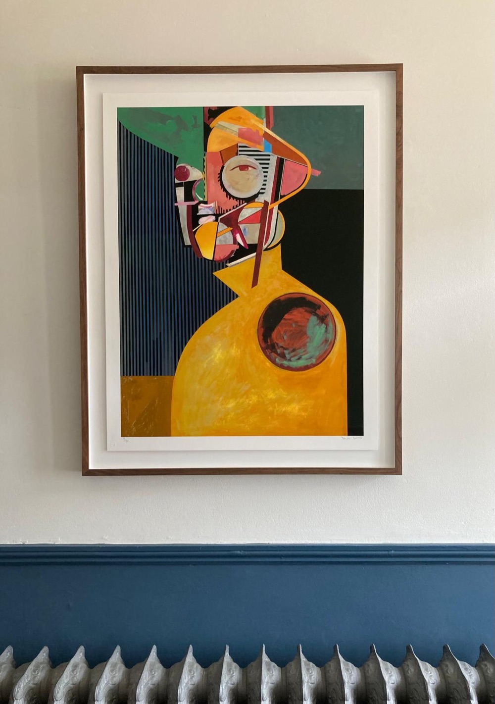 Framed abstract portrait print in a walnut frame above a blue dado rail