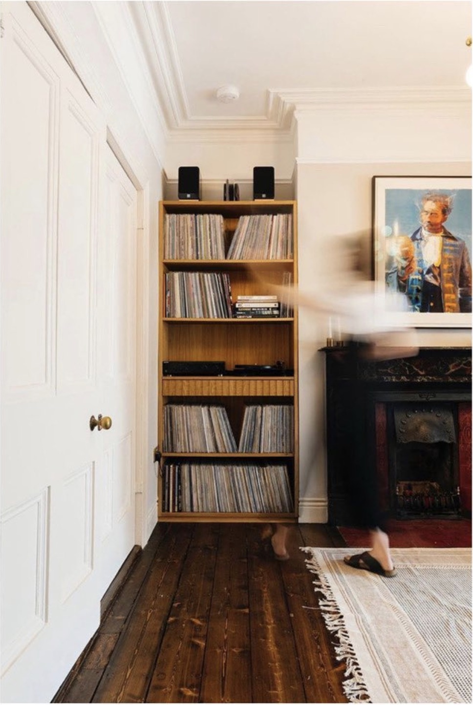 Living room with a shelving unit of vinyl records beside a large framed portrait above the fireplace
